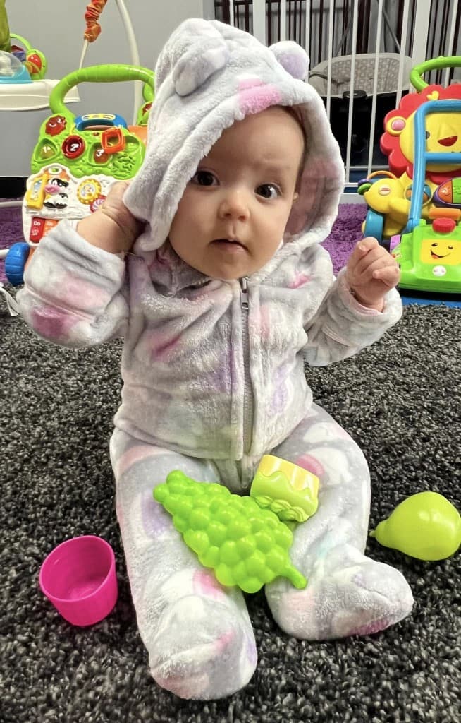 Baby in a cozy outfit sitting with toys